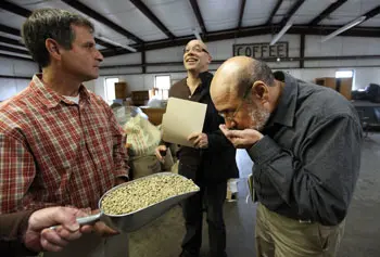 Raul Raudales sniffs arabica coffee beans as he and Richard Trubey, center, meet with Red Barn Coffee Roasters President Mark Verrochi to discuss the coffee drying process.