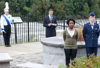 From left, Kevin Webb, Field Conductor of the UMass Lowell Marching Band, readies to ring a chime while Christian Ellwood &nbsp;of the Student Veterans Organization reads the biography of John Ogonowski and Sade Jeanjacques &nbsp;of the Office of Multicultural Affairs and Alanna Kealy of Silver Wings look on.