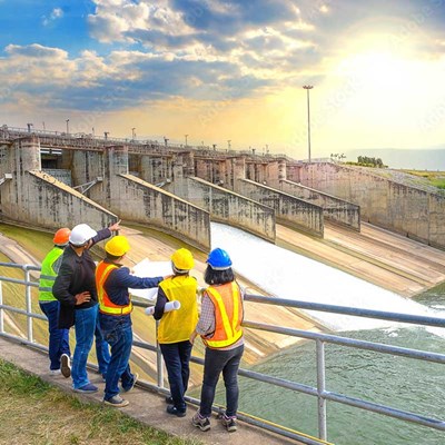 People in hard hats and safety vests looking out a dam.