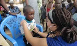 Alex Lamont of Lowell checks a child&rsquo;s heart in the village of Torkor.