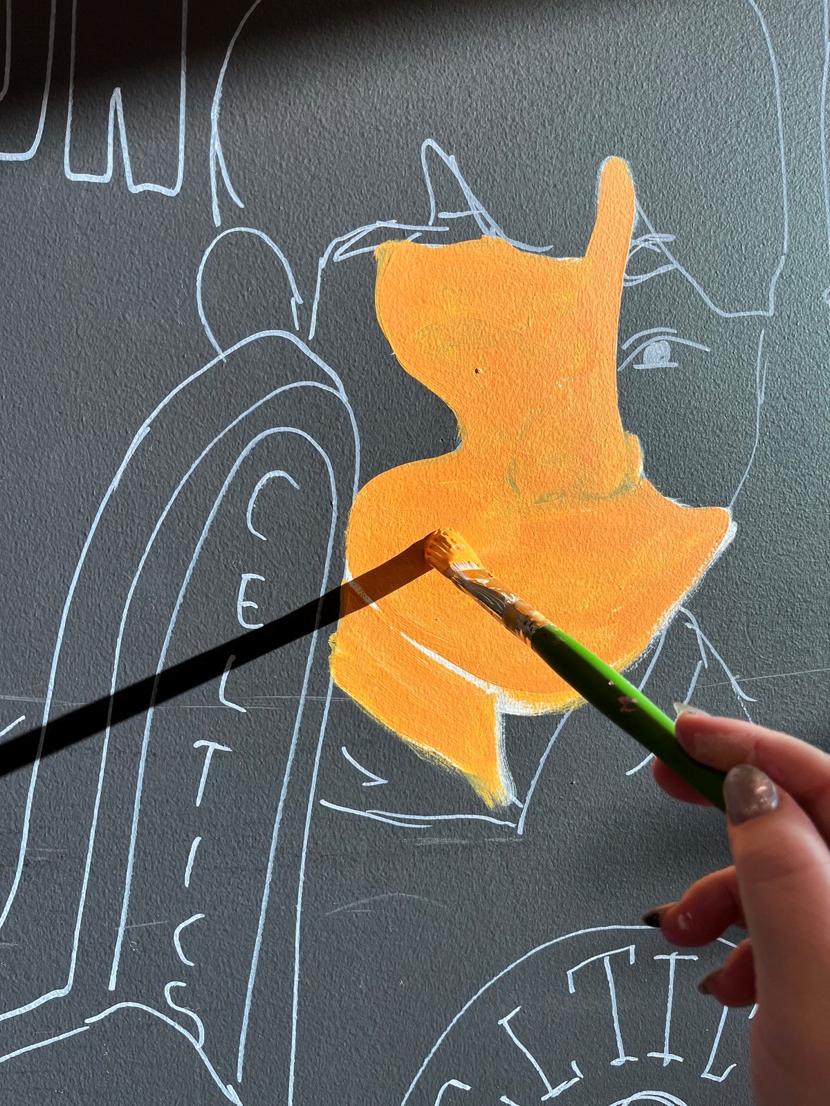 A closeup of a paint brush painting an orange face on a while.
