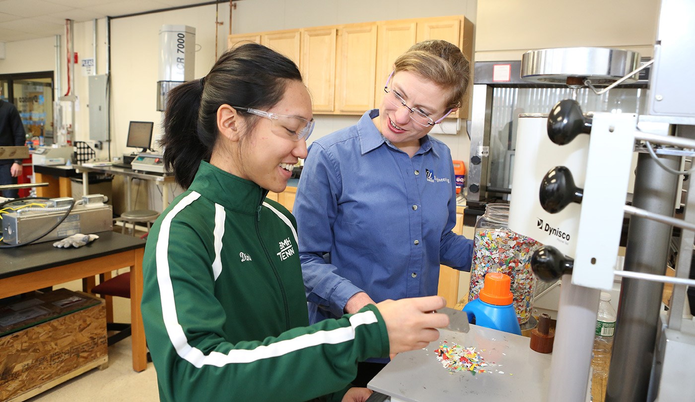 Asst. Prof. Meg Sobkowicz-Kline demonstrating things to a female student in the plastics recycling lab.