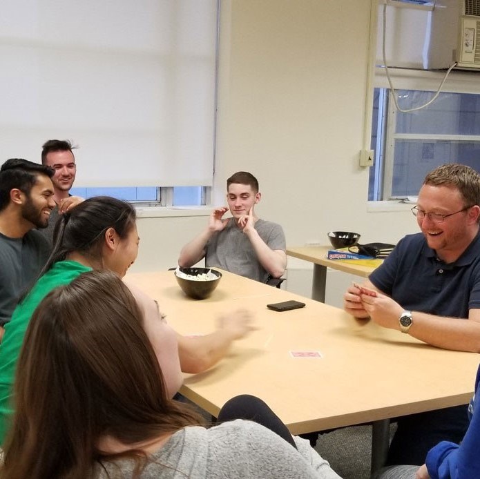 Group of students play cards around table