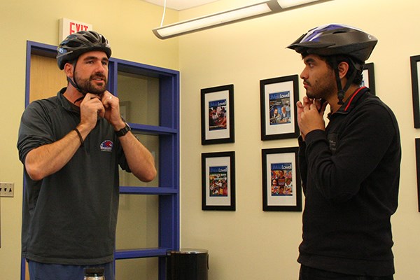 Kevin Soleil helps Hannan Shafiq fit a bike helmet