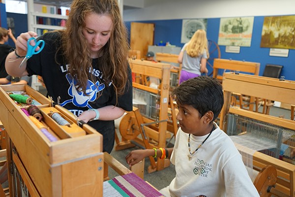 National Park Adventures Camp junior counselor Lauren Fleury helps camper Sharad Patel change colors in the weaving classroom at Lowell National Historical Park