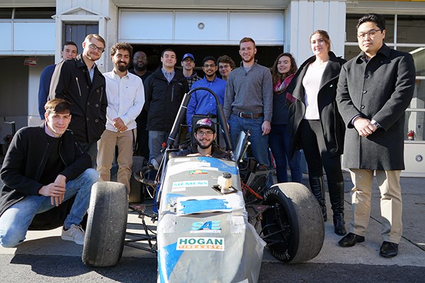 Business and engineering students pose with the River Hawk Racing car from 2017 competition