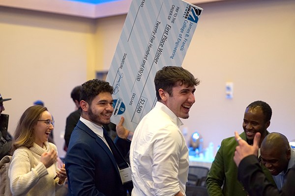 Students smile and celebrate while holding an oversized check