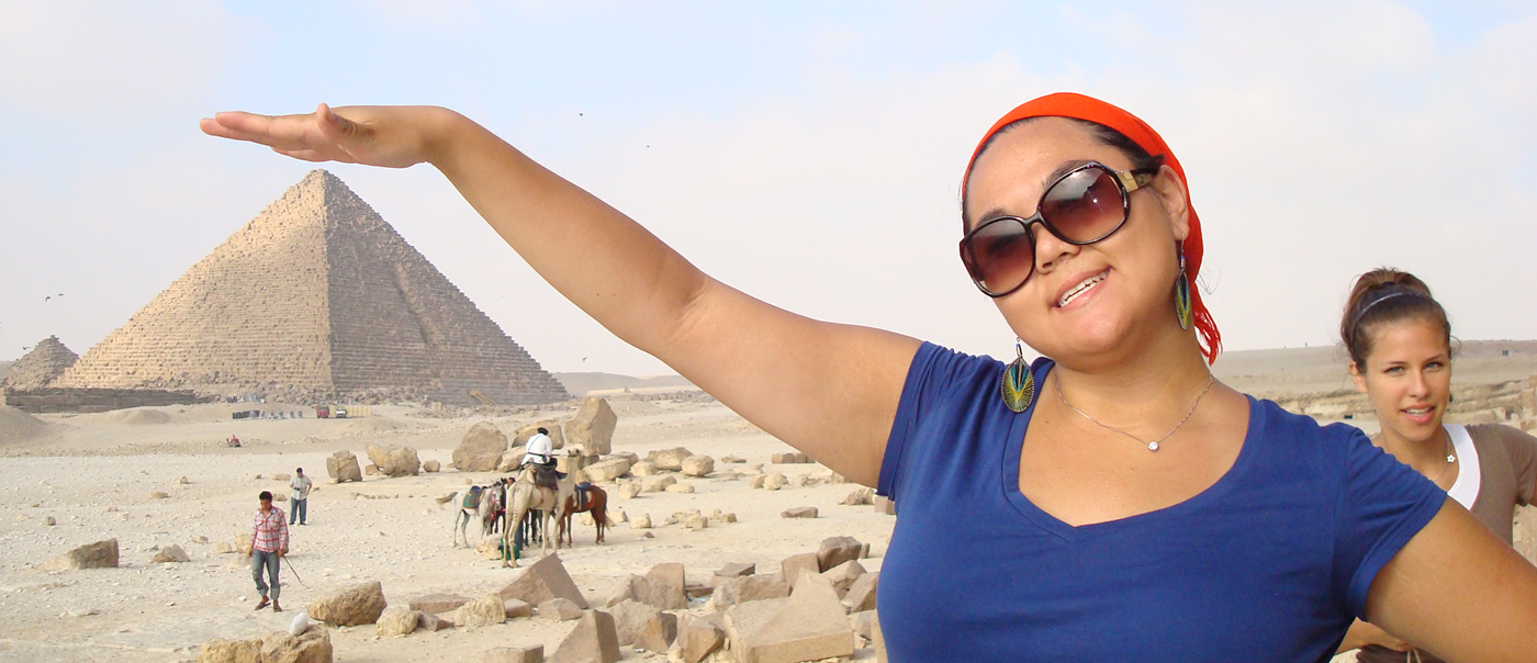 Student poses with hand over pyramid in far distance in Egypt.