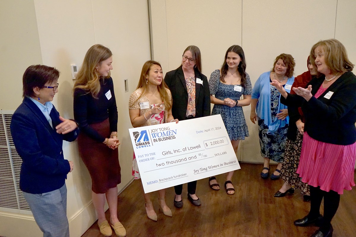 A person holds an oversized check while seven other people look on.