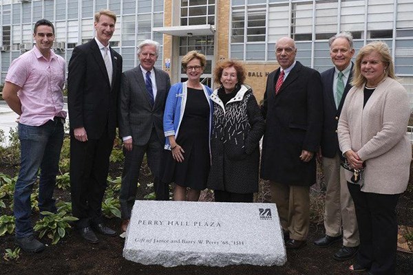 Eight people stand in front of Perry Hall Plaza stone