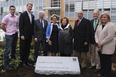 Eight people stand in front of Perry Hall Plaza stone
