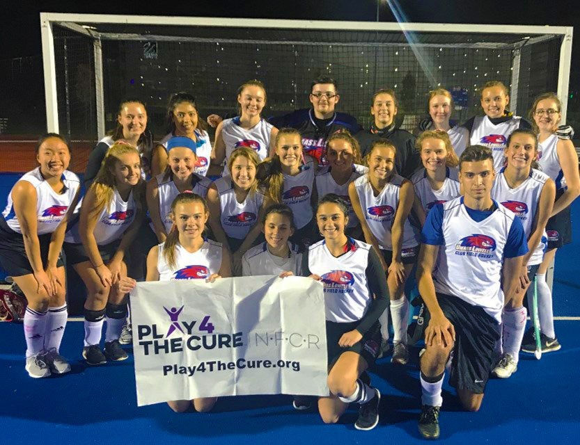 Field Hockey team posing after a charity game with a banner