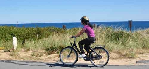 A female student riding a bike provided by the "free wheeler's" program near a cape.