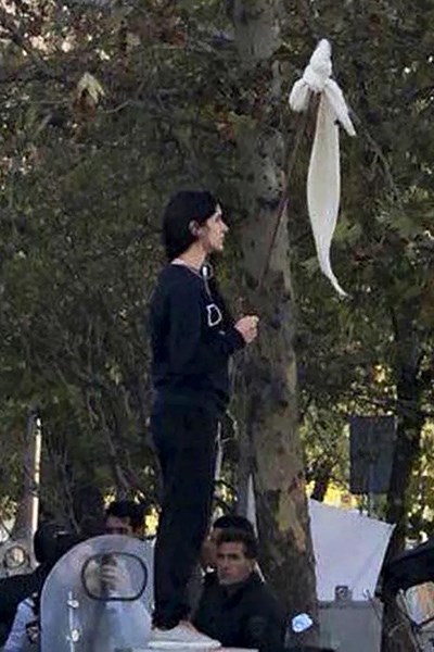 The Girl of Revolution Street stands on an electrical box with her hijab removed and tied to a stick like a flag, in a protest for women's rights in Iran