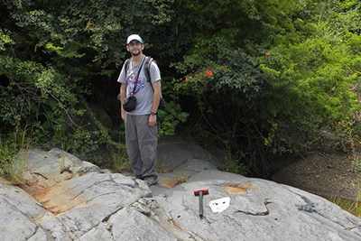 Richard Gaschnig stands on rock with hammer at feet