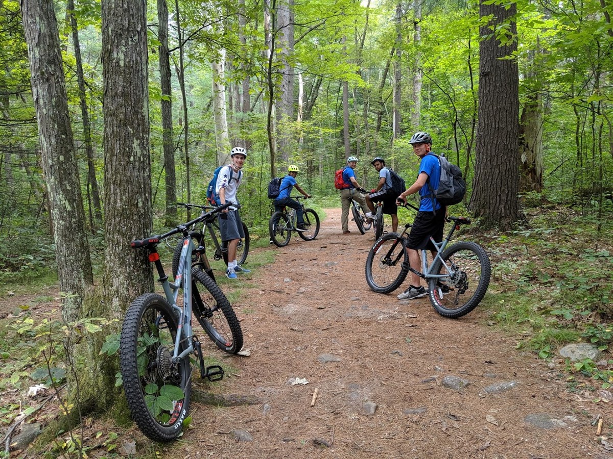 Mountain bikers mounted on their bikes and looking back at the camera at Great Brook State Park.