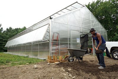 Mill City Grows staff spread compost inside the greenhouse