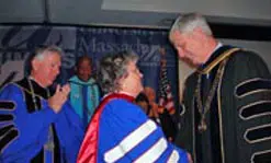 UMass President Jack Wilson adorns Barbara Hogan with her honorary doctorate as UMass Lowell Chancellor Marty Meehan applauds.
