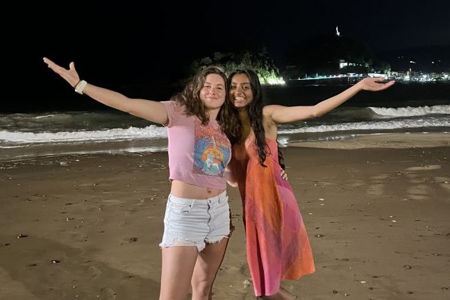 Two female college students pose for a photo at night on the beach