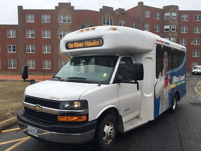 UMass Lowell Transportation shuttle bus with Go River Hawks! sign.