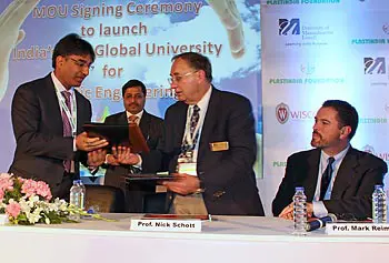 Plastics Engineering Prof. Emeritus Nick Schott, second from right, exchanges documents with Ashok Goel, president of Plastindia Foundation, during the signing ceremony in New Delhi, India. Looking on at right is Mark Reimer of UMass Lowell&rsquo;s Office of University Advancement.
