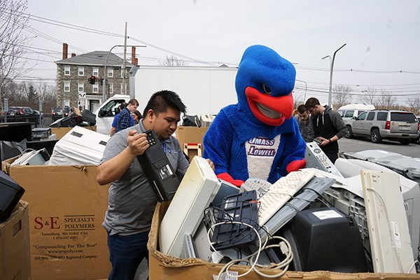 Rowdy the River Hawk helps student Andre Ragel sort recycled computer items