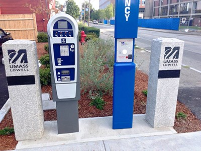 Parking Meter next to UMass Lowell stone pillars and emergency call box station.