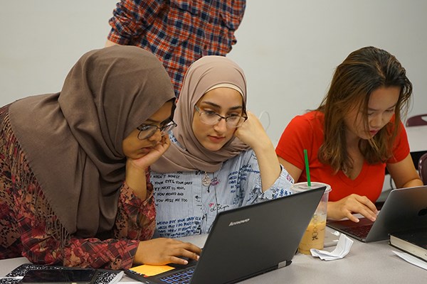 Sophomore Sarah Kamal assists incoming first-year engineering student Salwa Alhawi at UMass Lowell's RAMP camp, while Junyuan Hu works on a computing problem