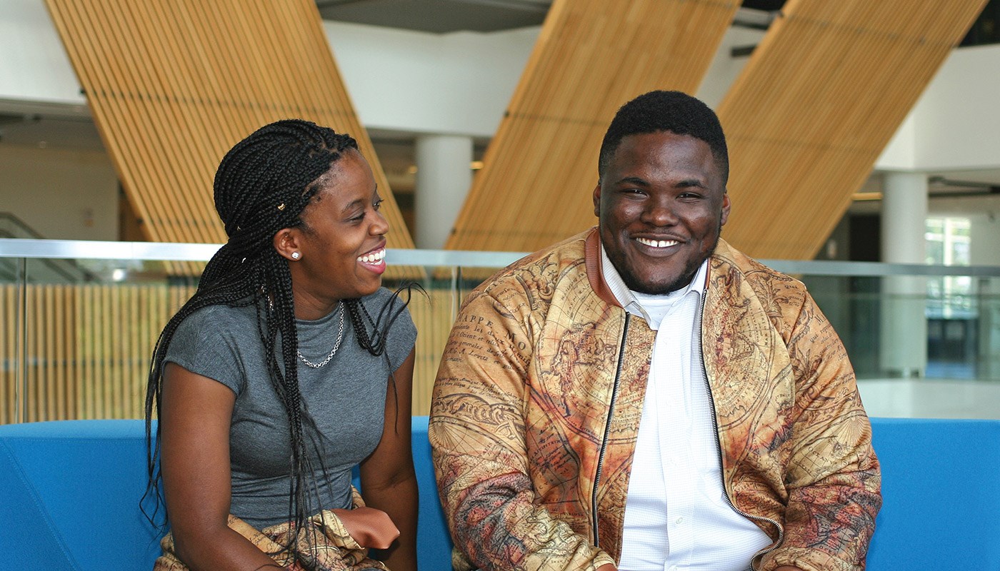 Electrical engineering alumnus and clothing designer Richard Asirifi laughing with friend at University Crossing