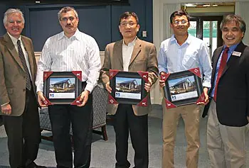 Chancellor Marty Meehan, far left, and Engineering Dean John Ting, far right, present framed photos of the 4D Home built by Team Massachusetts to, from left, Boris Serebrennikov, Oh-Hun Kwon and Mithun Kamath of Saint-Gobain.