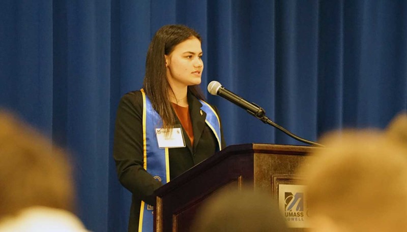 UMass Lowell student Sarah Curley delivers a speech while standing at a lectern.