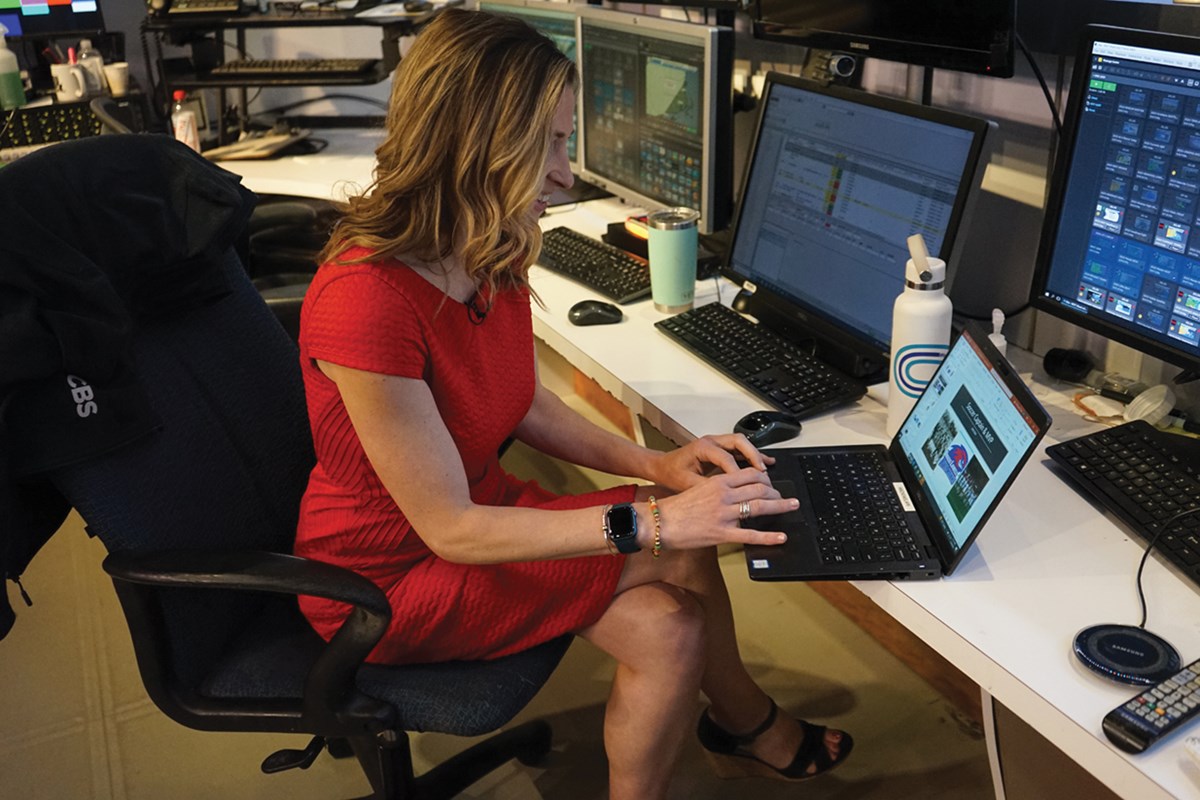 Meteorologist Sarah Wroblewski works on a laptop in the studio