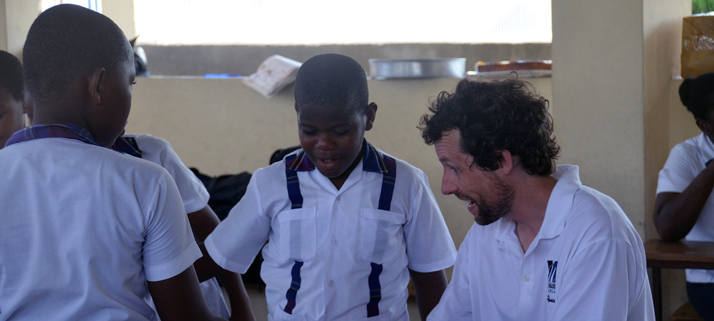UMass Lowell Physics Lecturer teaching two young Haitian boys on a trip to Haiti in 2016.