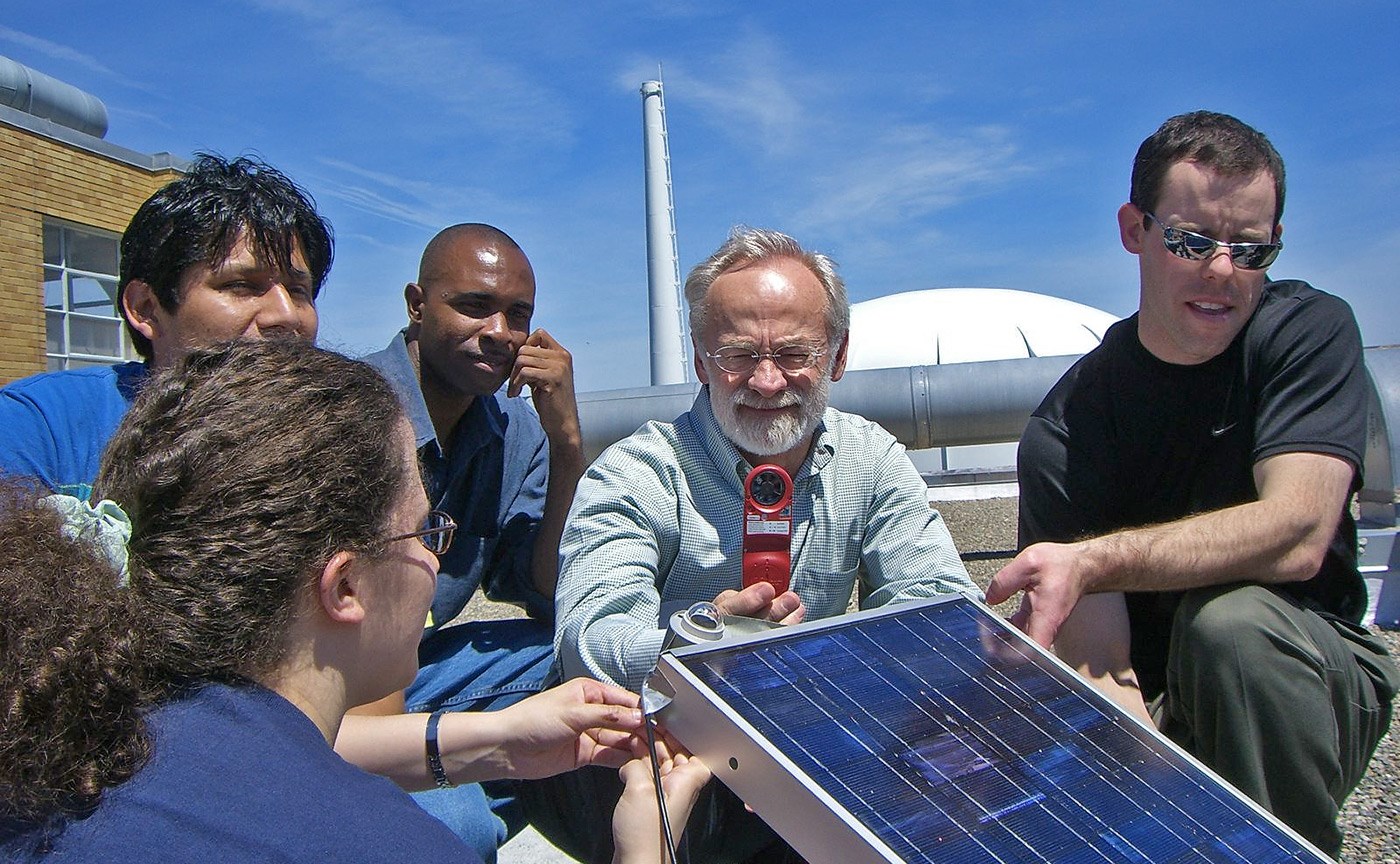 Professor John Duffy and four UMass Lowell students working on a solar panel project.