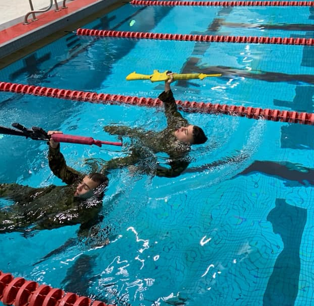 Two Cadets swimming with dummy rifles