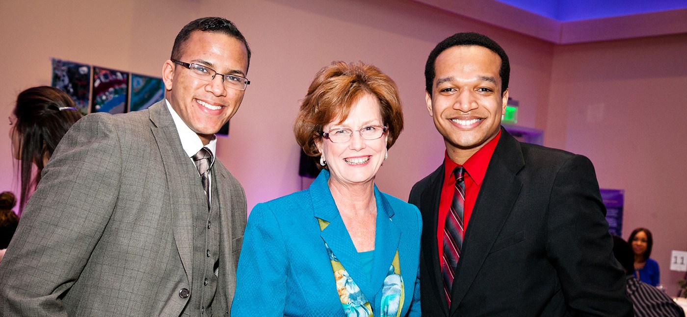 2 male students pose for a picture with Chancellor Jacquie Moloney at the 2015 MLK awards dinner.