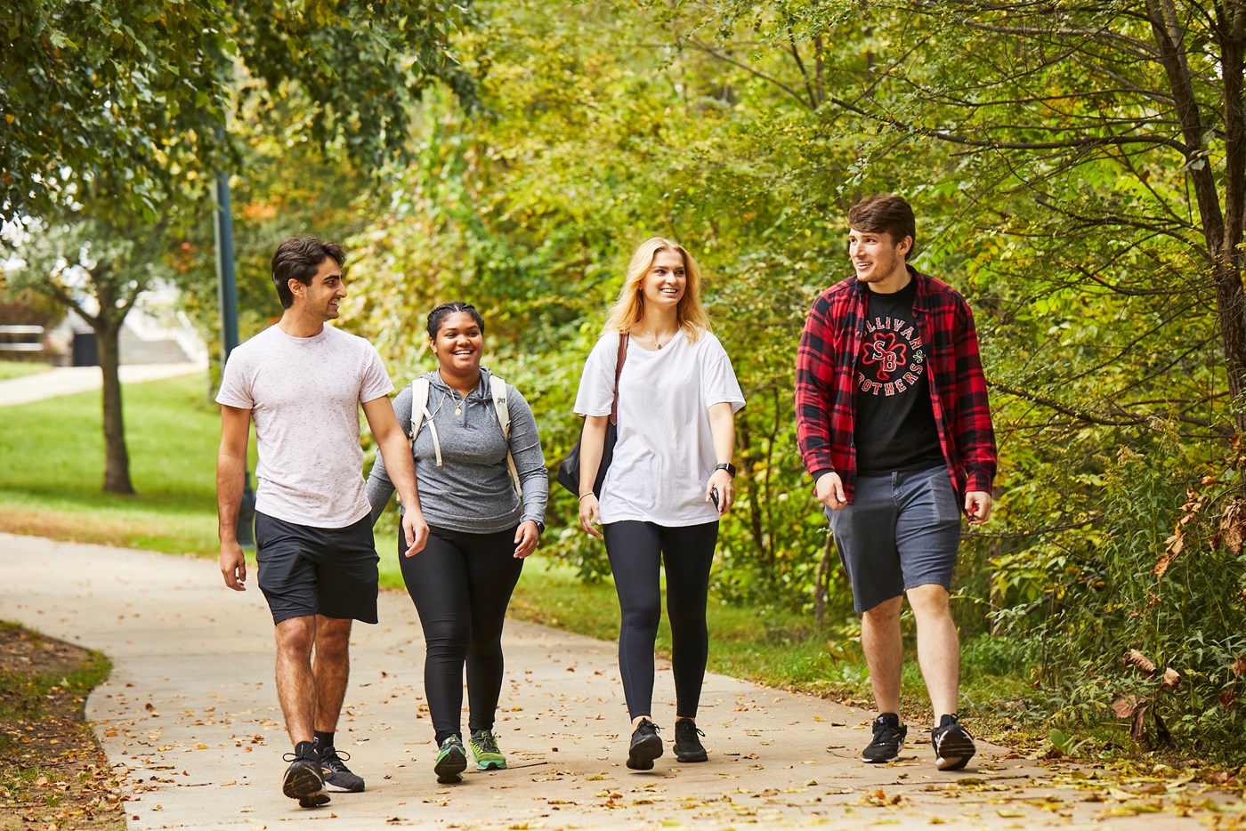 Four students walking on path