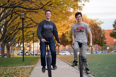 Evan Jones and Andrew Terrill ride their unicycles on East Campus