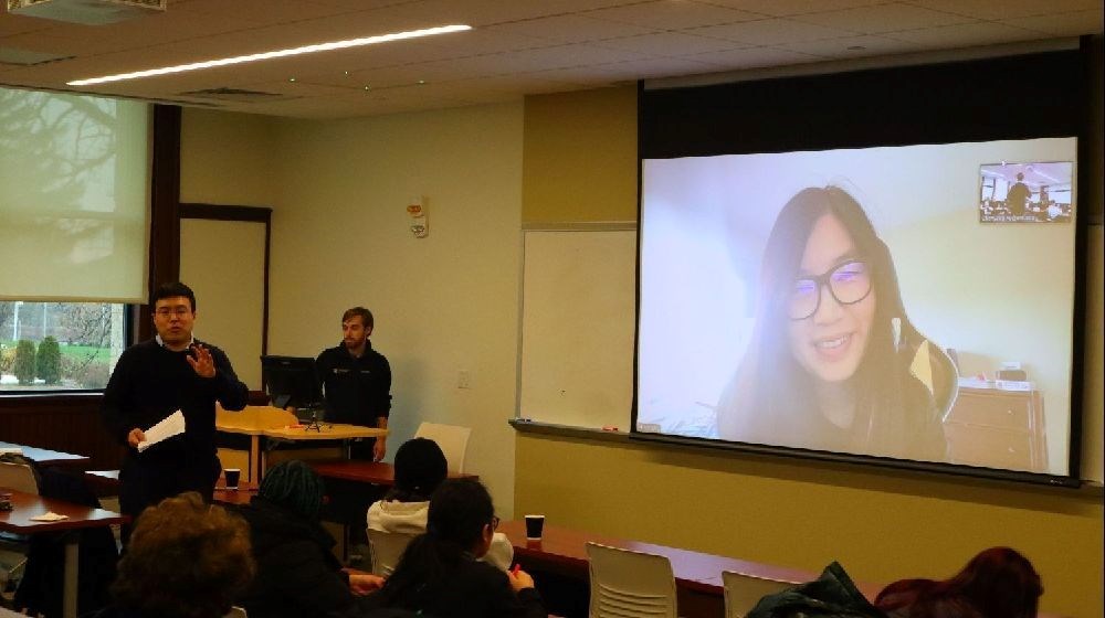 Amazon economist on tv screen talking to a class of UMass Lowell students and professor.