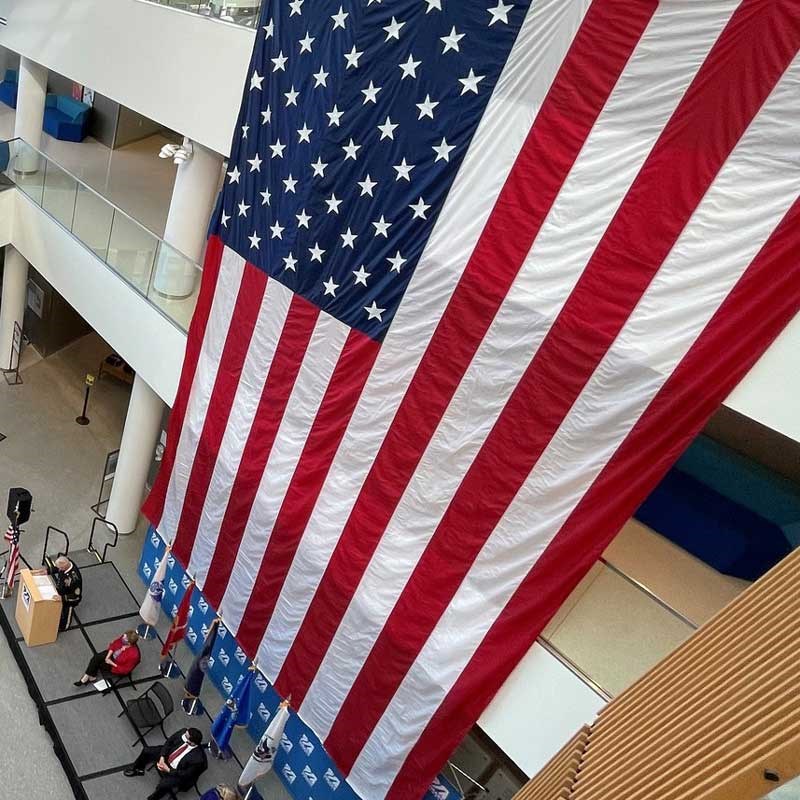 America flag hangs above speakers at the Annual Flag Ceremony that celebrates UMass Lowell student and alumni veterans and veterans in the community