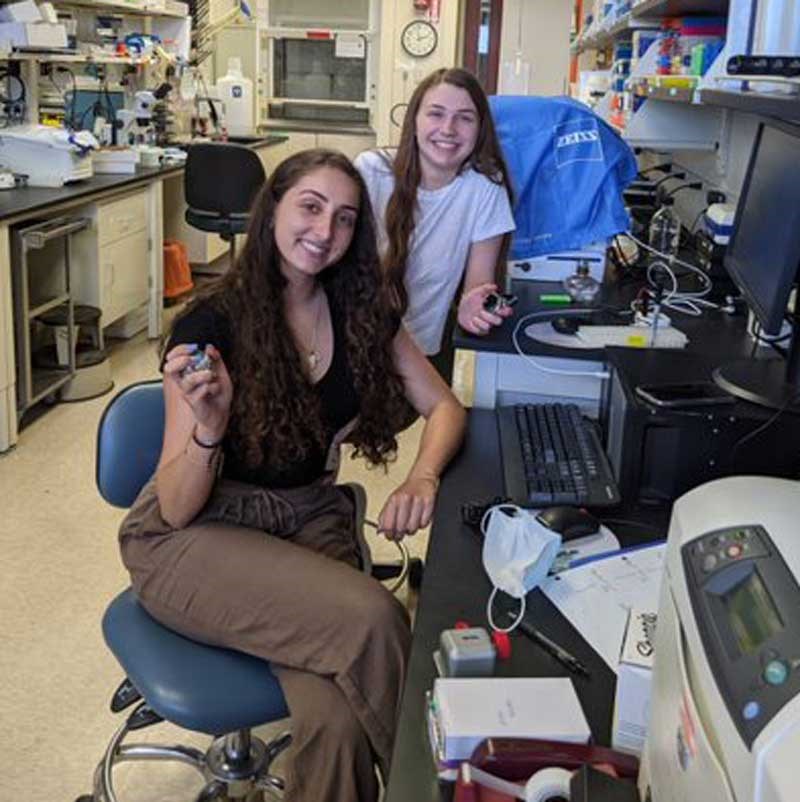 Two students holding equipment in a biotechnology lab at UMass Lowell