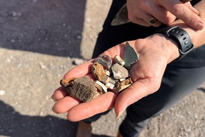 A student holds stones and archeological artifacts in their hand