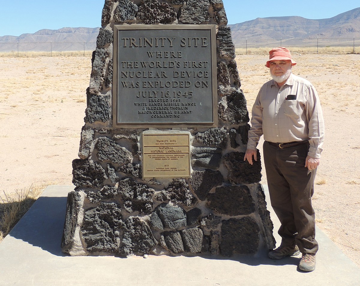 Professor Nelson Eby poses next to the Trinity Site monument. Eby's general area of research is geochemistry. Recent projects - characterizing the glass (Trintite) produced during the first atomic bomb test; petrology and geochemistry of Jurassic - Cretaceous magmatism in the northeastern US and Canada; petrology and geochemistry of the Chilwa Alkaline Province, Malawi; origin of the Franklin and Sterling Hill ore deposits; F and Cl in apatite, amphibole, and biotite; using tree-ring cores to map environmental change; and source and distribution of atmospheric pollutants.
