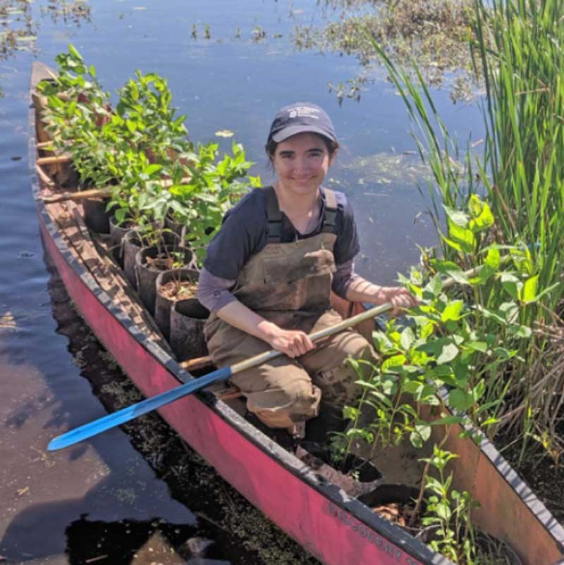 Student in a canoe that is filled with plants in containers