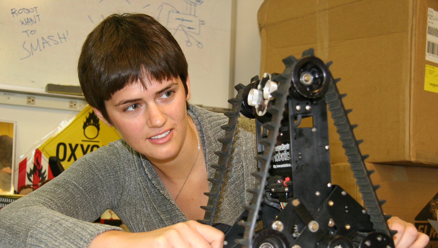 female-student-looking-at-treaded-robot-cs-robotics