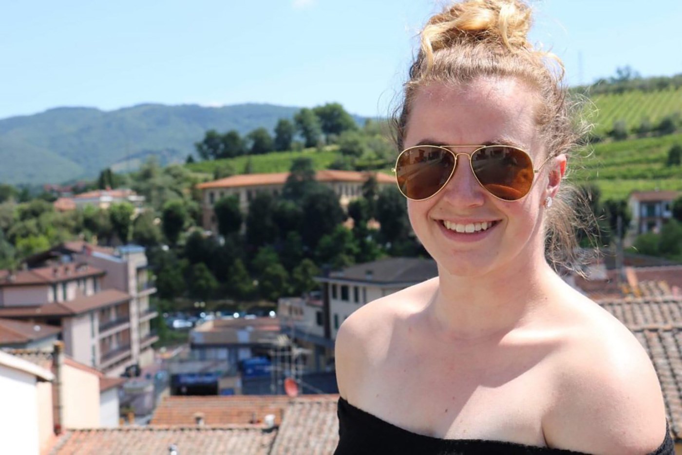 UMass Lowell student, Sarah George poses with a beautiful backdrop of the Tuscany, Italy.