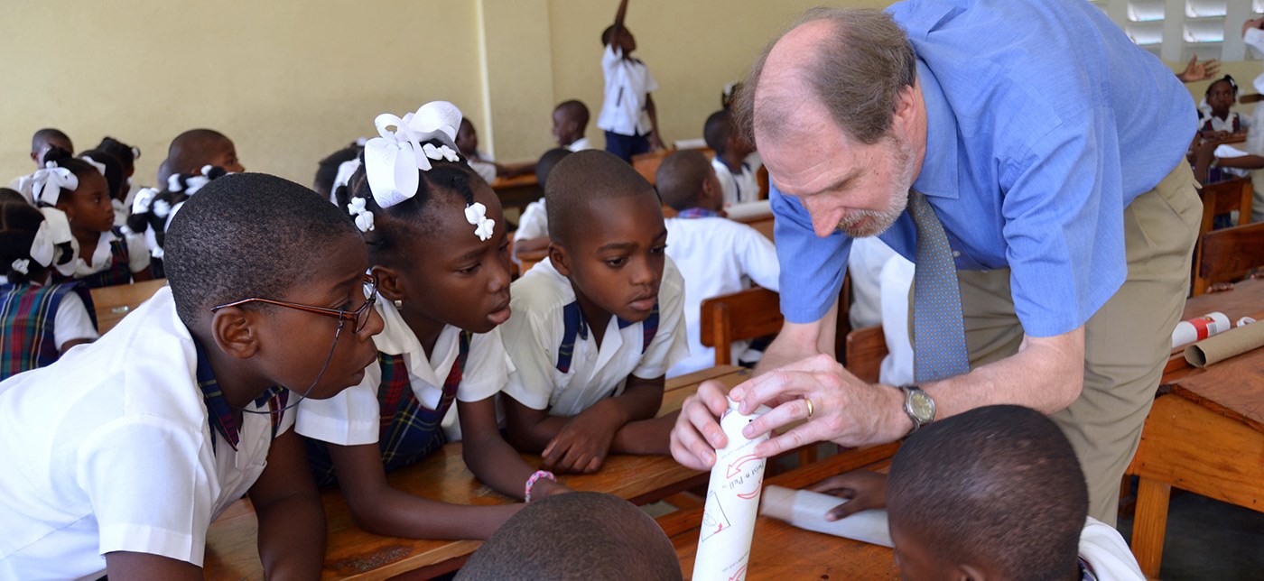 UMass Lowell Professor and Director of the Haiti Development Studies Center teaches schoolchildren in Les Cayes, Haiti, how to build a simple telescope out of cardboard tubes and lenses as part of the Haiti Development Studies Center’s astronomy education outreach.