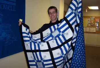 Graduate student Neil MacDonald displays the handmade quilt he won in a raffle sponsored by the GSE&rsquo;s Graduate Student Organization to raise money for the House of Hope family shelter.