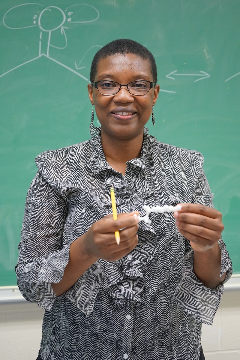 Organic chemistry professor Khalilah Reddie smiles in a classroom at UMass Lowell in front of chalkboard