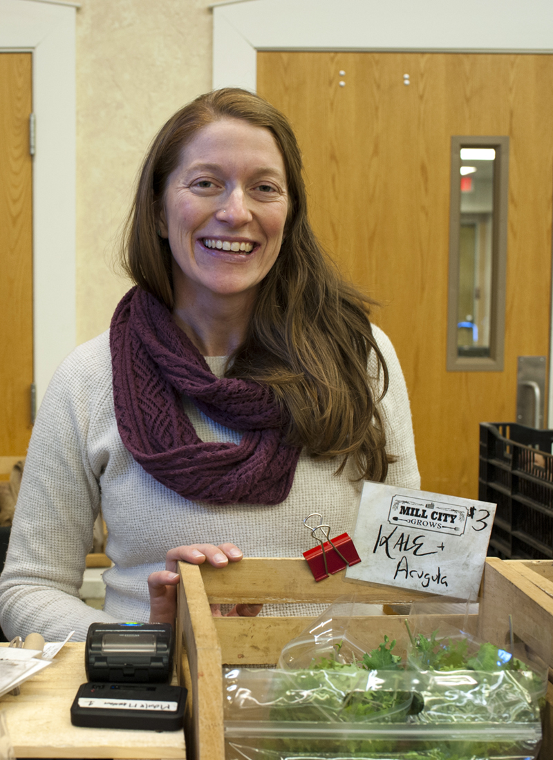Lydia Sisson smiles behind the register at an indoor farmers market
